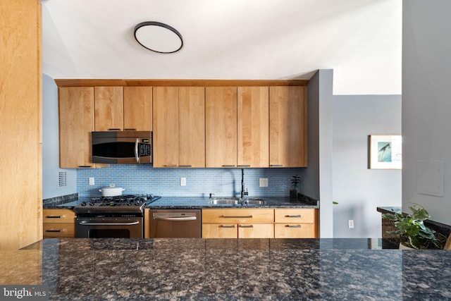 kitchen featuring tasteful backsplash, dark stone countertops, sink, and appliances with stainless steel finishes