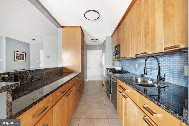 kitchen featuring tasteful backsplash, dark stone countertops, sink, and stainless steel appliances