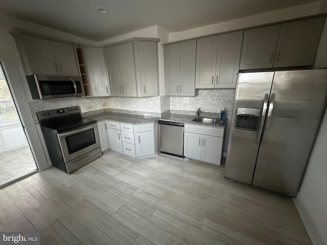 kitchen featuring gray cabinetry, backsplash, appliances with stainless steel finishes, and light hardwood / wood-style flooring