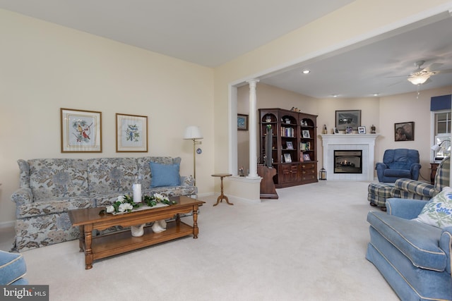 living room featuring decorative columns, a tiled fireplace, ceiling fan, and carpet floors