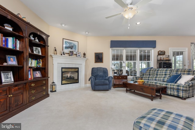 living room featuring ceiling fan, light carpet, and a tile fireplace