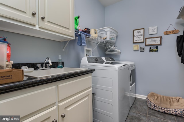 clothes washing area featuring washing machine and dryer, sink, cabinets, and dark tile patterned flooring