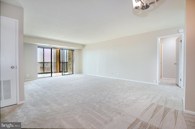 empty room with a notable chandelier and light colored carpet