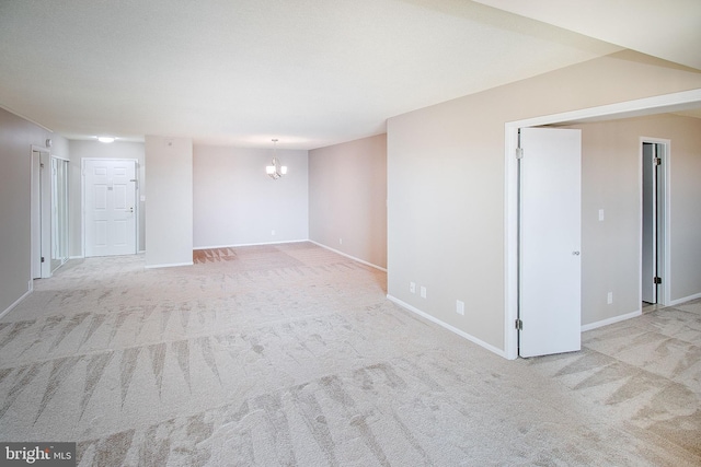 carpeted spare room with an inviting chandelier