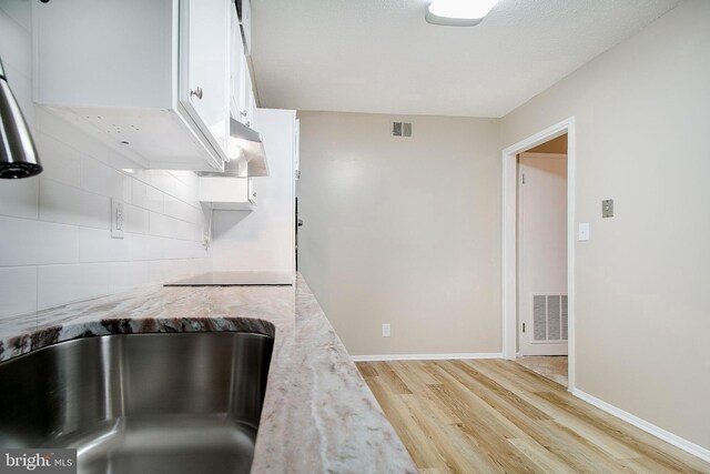 5901 Mount Eagle Dr Unit 1101, Alexandria, VA 22303 - kitchen with light wood finished floors, white cabinets, light stone counters, backsplash, and baseboards