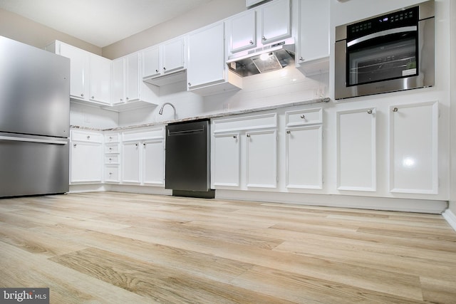 kitchen with decorative backsplash, light stone counters, stainless steel appliances, light hardwood / wood-style flooring, and white cabinetry