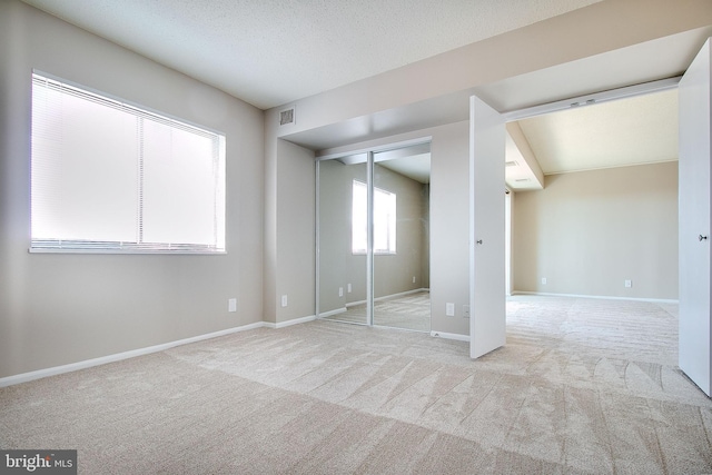 unfurnished bedroom featuring a closet, light colored carpet, and a textured ceiling