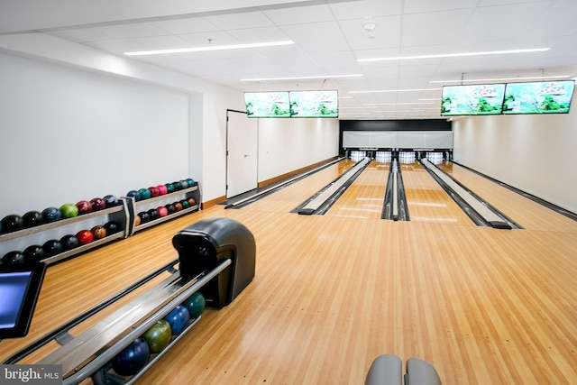 game room with a drop ceiling, a bowling alley, and hardwood / wood-style flooring