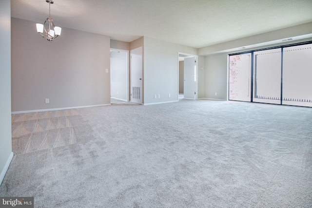 carpeted spare room with a chandelier