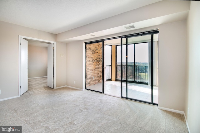 unfurnished bedroom with a textured ceiling, access to exterior, and light carpet