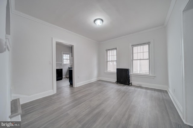 unfurnished living room with crown molding, radiator, and hardwood / wood-style floors