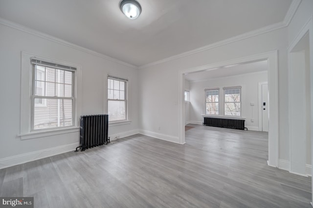 unfurnished living room featuring a wealth of natural light, radiator heating unit, and light wood-type flooring