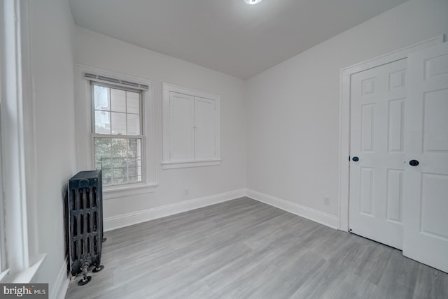 empty room featuring radiator heating unit and light wood-type flooring