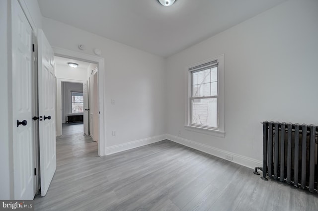 empty room featuring radiator heating unit, light hardwood / wood-style flooring, and a wealth of natural light