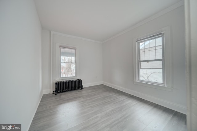 empty room featuring crown molding, radiator heating unit, and light hardwood / wood-style floors