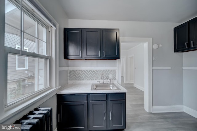 kitchen with tasteful backsplash, sink, and light hardwood / wood-style floors