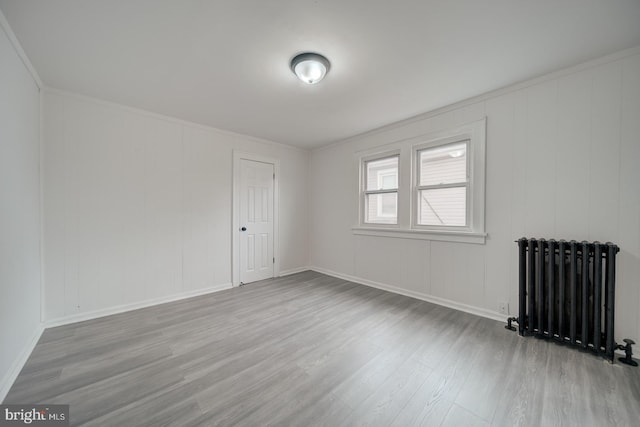 spare room featuring ornamental molding, radiator, and light hardwood / wood-style floors