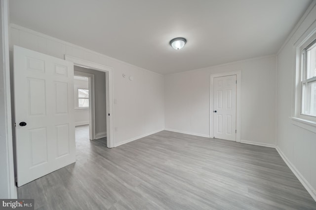 spare room with ornamental molding, plenty of natural light, and light hardwood / wood-style floors