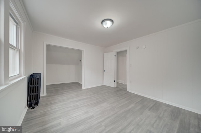 unfurnished room featuring a healthy amount of sunlight, radiator, and light hardwood / wood-style floors