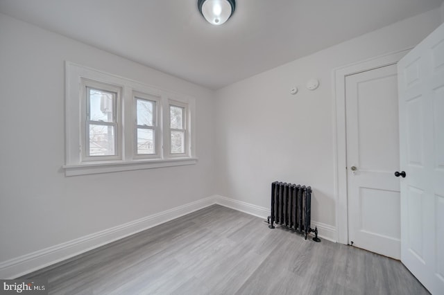 empty room featuring radiator heating unit and light wood-type flooring