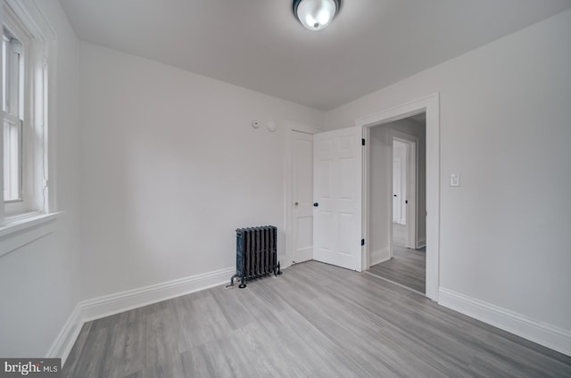 unfurnished room featuring light hardwood / wood-style flooring and radiator heating unit