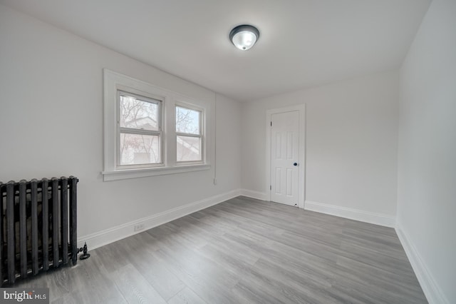 spare room featuring radiator and light wood-type flooring