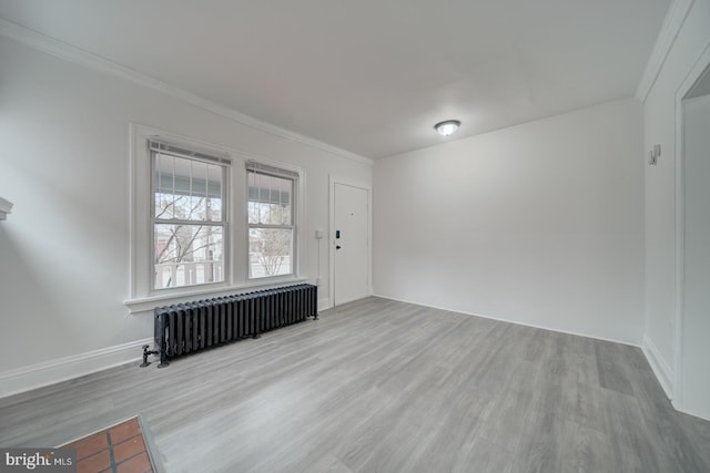 spare room with radiator, crown molding, and light hardwood / wood-style flooring