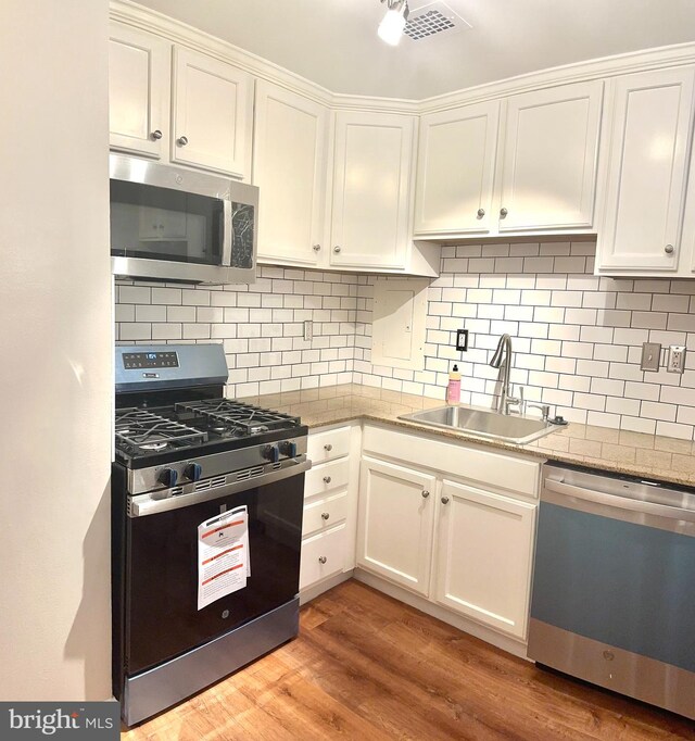 kitchen with stainless steel appliances, light hardwood / wood-style flooring, white cabinetry, and sink