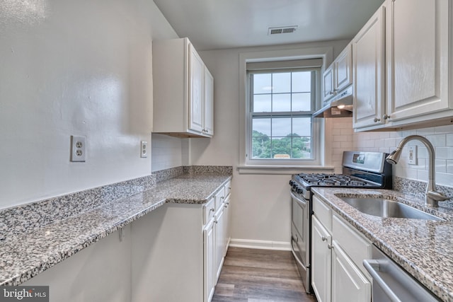 kitchen featuring white cabinets, sink, hardwood / wood-style flooring, appliances with stainless steel finishes, and tasteful backsplash