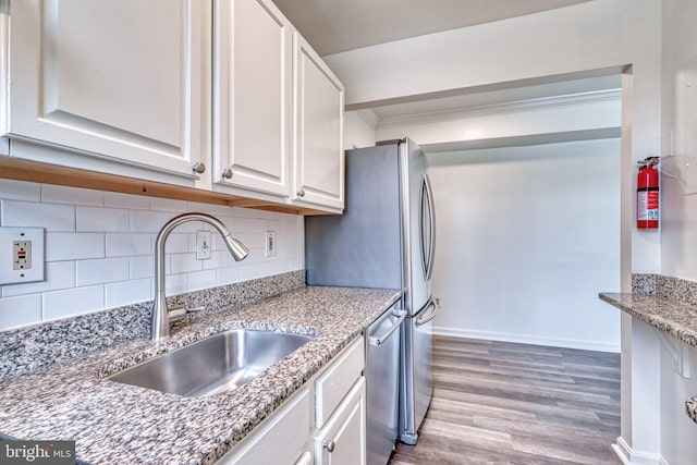 kitchen featuring white cabinetry, sink, light hardwood / wood-style flooring, backsplash, and appliances with stainless steel finishes