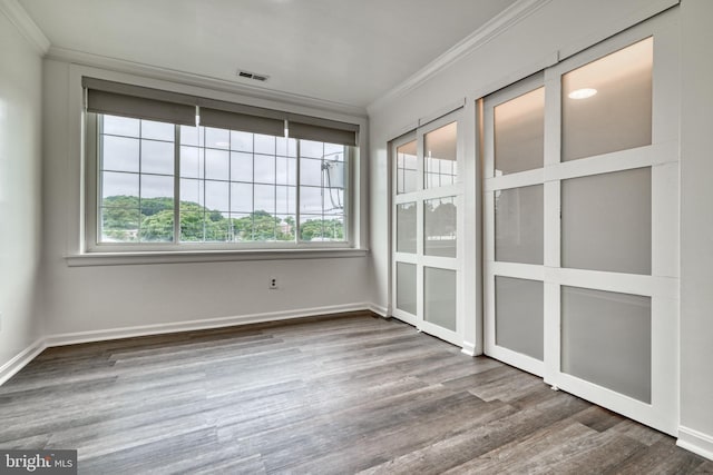 unfurnished room with crown molding, a healthy amount of sunlight, and wood-type flooring