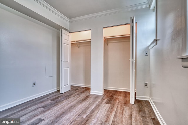 unfurnished bedroom featuring hardwood / wood-style floors, two closets, and ornamental molding