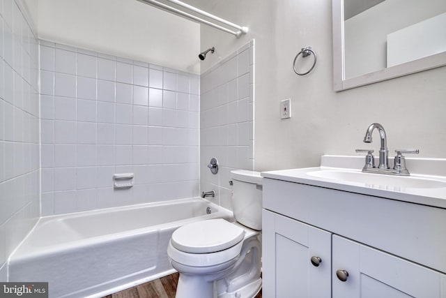 full bathroom with hardwood / wood-style floors, tiled shower / bath combo, toilet, and vanity