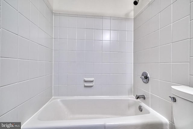 bathroom featuring toilet and tiled shower / bath