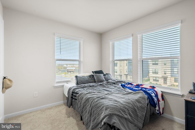 bedroom featuring light colored carpet and multiple windows