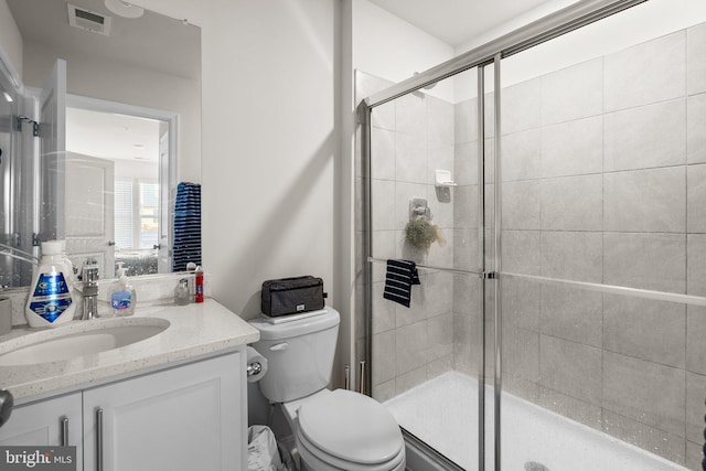 bathroom featuring vanity, toilet, and a shower with door