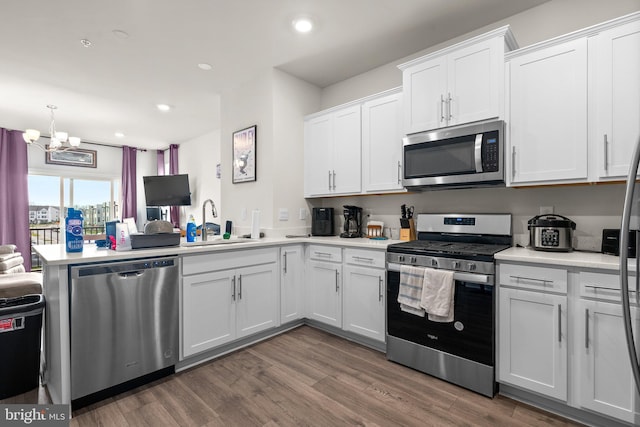 kitchen featuring sink, stainless steel appliances, dark hardwood / wood-style floors, a chandelier, and white cabinets