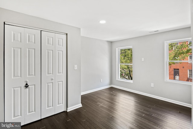 unfurnished bedroom featuring dark wood-type flooring and a closet