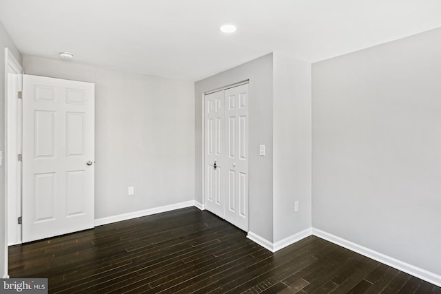 unfurnished bedroom featuring dark hardwood / wood-style flooring and a closet