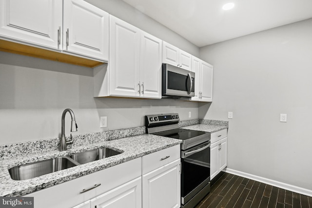 kitchen featuring sink, appliances with stainless steel finishes, dark hardwood / wood-style flooring, light stone counters, and white cabinetry