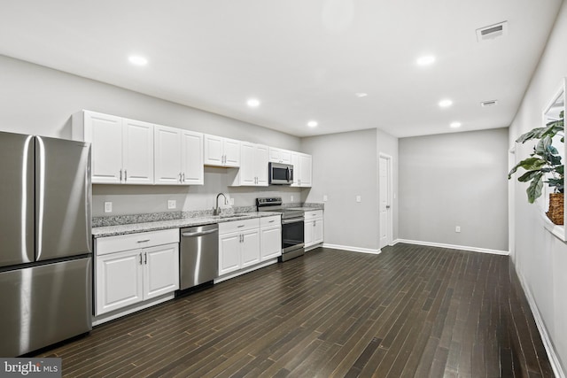 kitchen with white cabinets, sink, dark hardwood / wood-style floors, appliances with stainless steel finishes, and light stone counters