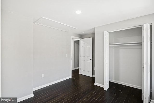 unfurnished bedroom with a closet and dark wood-type flooring