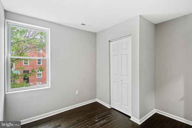 unfurnished bedroom featuring dark hardwood / wood-style flooring and a closet