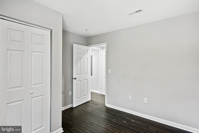 unfurnished bedroom featuring dark wood-type flooring and a closet