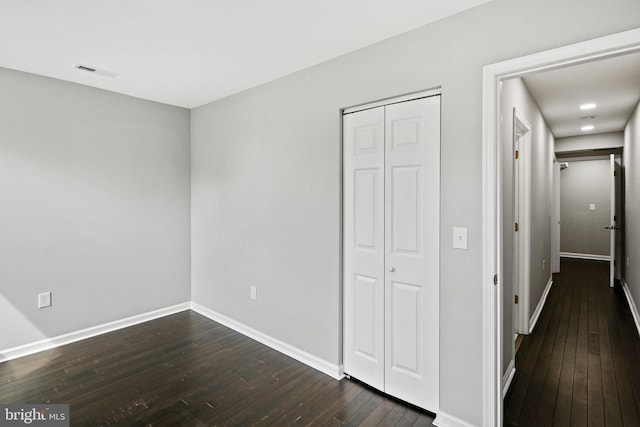 unfurnished bedroom with a closet and dark hardwood / wood-style flooring