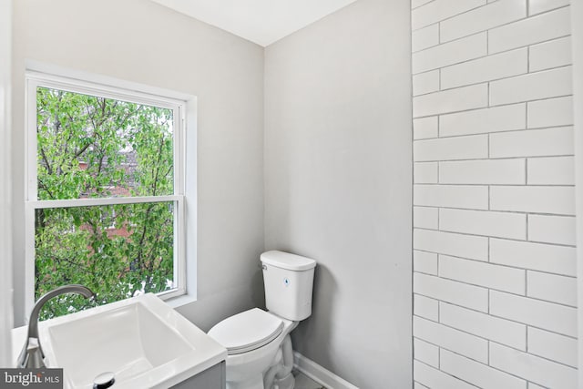 bathroom with a healthy amount of sunlight, toilet, and sink