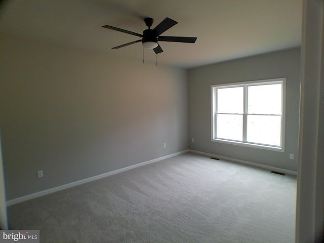 spare room featuring carpet floors, visible vents, ceiling fan, and baseboards