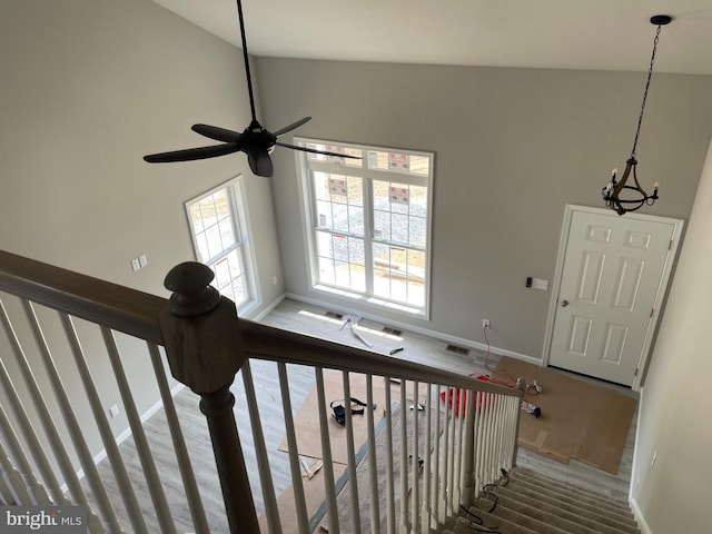 stairway featuring lofted ceiling, wood finished floors, visible vents, and baseboards