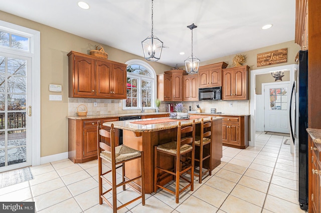 kitchen featuring a kitchen breakfast bar, black appliances, light tile patterned floors, a chandelier, and a center island