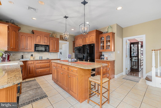 kitchen with sink, black appliances, light tile patterned floors, decorative light fixtures, and a center island